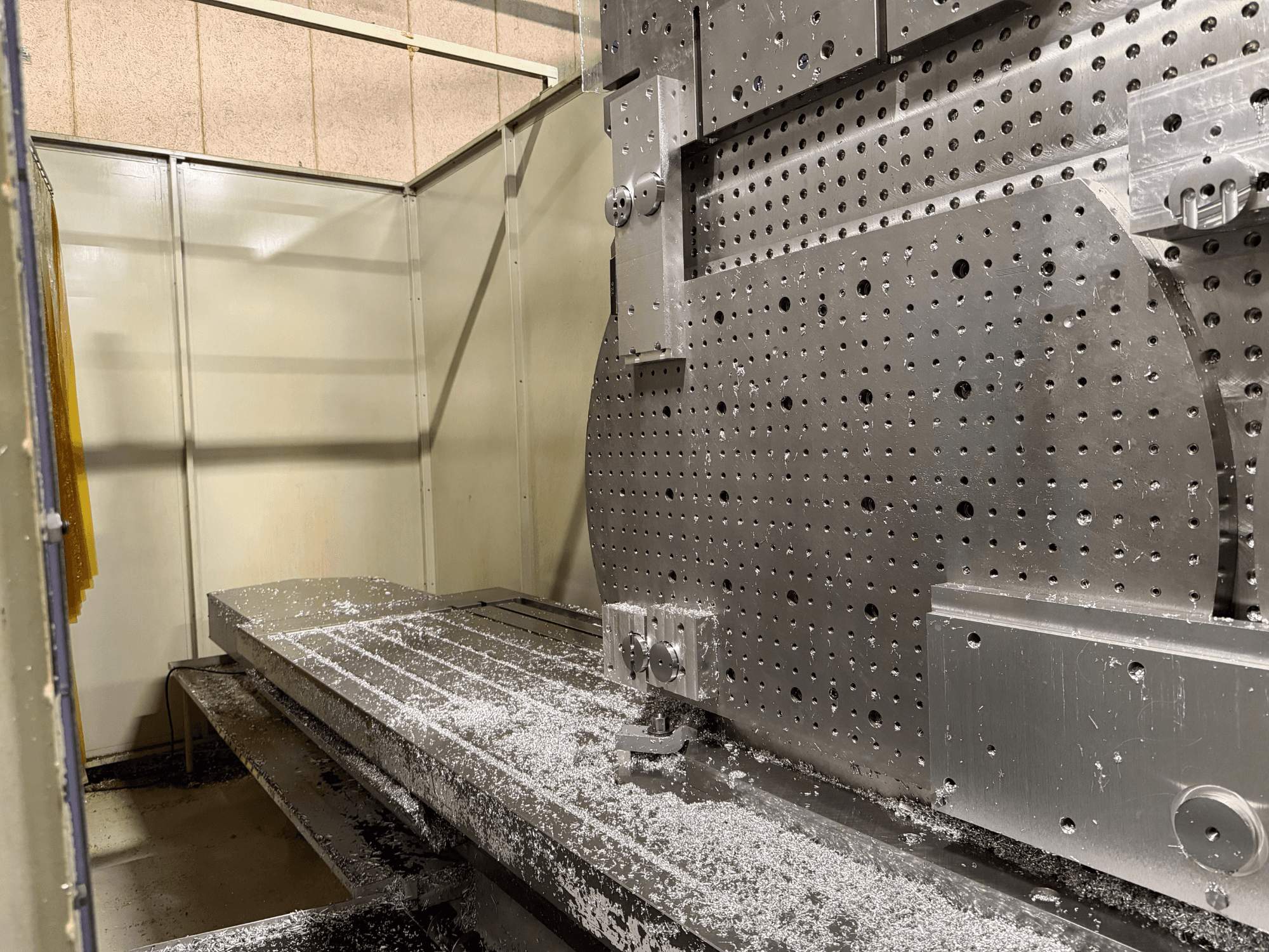 Vista frontale ravvicinata del Centro di lavoro universale KIHEUNG KNC-U1000, che mostra un tavolo di lavoro in metallo con trucioli di alluminio.