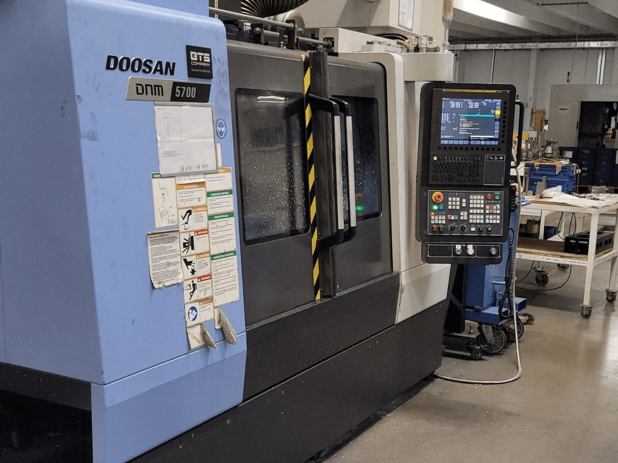 Centro di lavorazione verticale DOOSAN DNM 5700, vista frontale, con pannello di controllo e comandi operativi in primo piano.